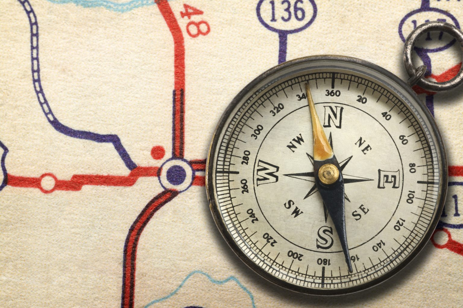 Compass sitting on top of road map showing highway junction