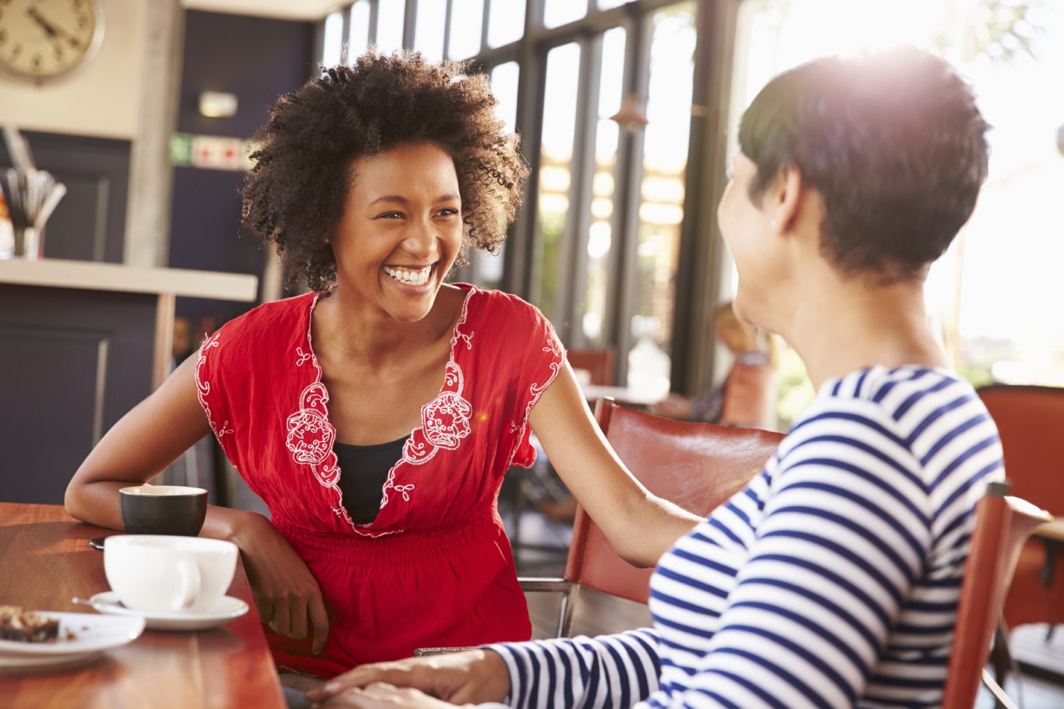 Two female friends talking at a coffee shop Two female friends talking at a coffee shop